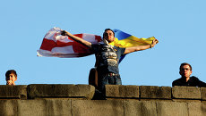 Человек держит флаги Грузии и Украины в Тбилиси Человек держит флаги Грузии и Украины в Тбилиси