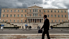 Мужчина проходит возле здания парламента Греции в Афинах. Архивное фото Мужчина проходит возле здания парламента Греции в Афинах. Архивное фото