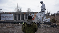Боец ополчения ЛНР возле памятника павшим в годы Великой Отечественной войны, Луганская область. Архивное фото Боец ополчения ЛНР возле памятника павшим в годы Великой Отечественной войны, Луганская область. Архивное фото
