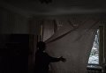 Женщина занавешивает поврежденное в результате обстрелов окно в Киевском районе Донецка Женщина занавешивает поврежденное в результате обстрелов окно в Киевском районе Донецка