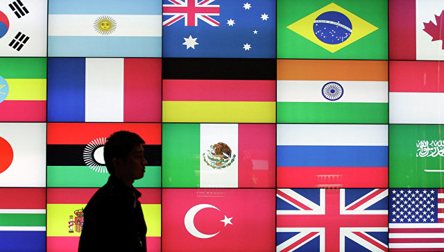 Мужчина проходит мимо экрана с флагами стран G20.  Архивное фото