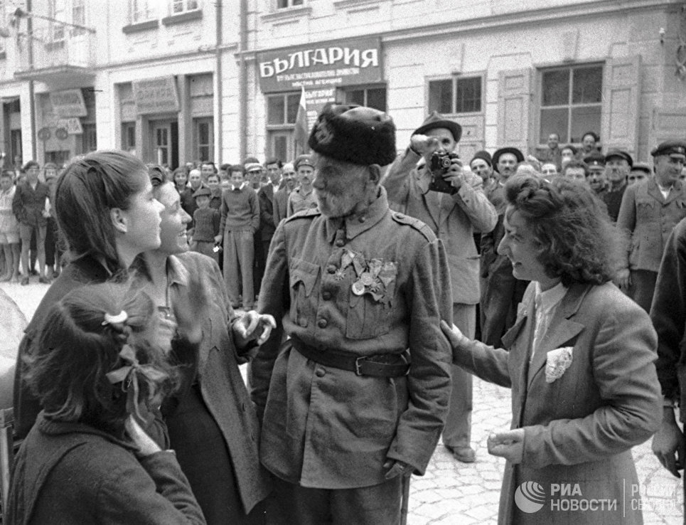 Ветеран турецкой войны беседует с девушками, в освобожденном войсками РККА от фашистов, болгарском городе