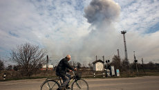 Мужчина на велосипеде на одной из улиц города Балаклея в Харьковской области во время пожара на военных складах боеприпасов Мужчина на велосипеде на одной из улиц города Балаклея в Харьковской области во время пожара на военных складах боеприпасов