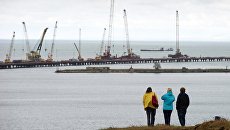 Люди наблюдают за строительством моста через Керченский пролив в Крыму. Архивное фото Люди наблюдают за строительством моста через Керченский пролив в Крыму. Архивное фото