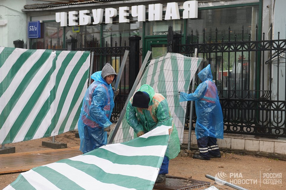 Строители поднимают сорванный ураганом заградительный забор на улице Остоженка в Москве Строители поднимают сорванный ураганом заградительный забор на улице Остоженка в Москве