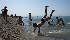 Отдыхающие на пляже Черного моря у детского оздоровительного лагеря в Крыму. Архивное фото Отдыхающие на пляже Черного моря у детского оздоровительного лагеря в Крыму. Архивное фото