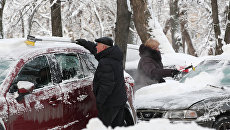 Горожане очищают личные автомобили от снега. Архивное фото Горожане очищают личные автомобили от снега. Архивное фото