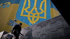 Женщина проходит мимо огромного украинского флага в центре Киева. Архивное фото Женщина проходит мимо огромного украинского флага в центре Киева. Архивное фото