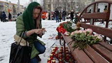Женщина зажигает свечу возле здания торгового центра «Зимняя вишня» в Кемерово, где произошел пожар Женщина зажигает свечу возле здания торгового центра «Зимняя вишня» в Кемерово, где произошел пожар