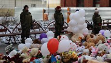 Охранники возле стихийного мемориала из цветов и игрушек в Кемерово. 5 апреля 2018 Охранники возле стихийного мемориала из цветов и игрушек в Кемерово. 5 апреля 2018