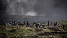 Палестинские протестующие во время столкновений с израильскими военными на границе сектора Газа и Израиля Палестинские протестующие во время столкновений с израильскими военными на границе сектора Газа и Израиля
