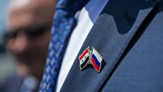 Значок с изображением флагов России и Сирии на пиджаке участника церемонии высадки оливковых деревьев в честь российско-сирийской дружбы высадили в Ялте Значок с изображением флагов России и Сирии на пиджаке участника церемонии высадки оливковых деревьев в честь российско-сирийской дружбы высадили в Ялте