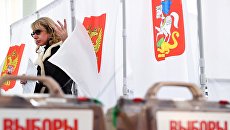 Девушка во время голосования на выборах. Архивное фото Девушка во время голосования на выборах. Архивное фото