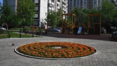 Детская игровая площадка и цветочная клумба во дворе дома Детская игровая площадка и цветочная клумба во дворе дома