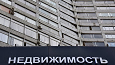 Вывеска с надписью Недвижимость на многоэтажном доме Вывеска с надписью Недвижимость на многоэтажном доме